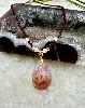 collier billes grenade facettées alternées des perles en métal doré avec un pendentif corail fossile