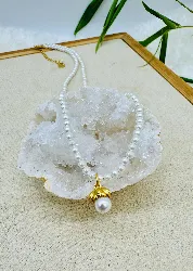 collier perles synthétiques avec un pendentif en perle surmontée d'une fleur en métal doré